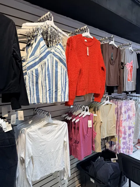 Exhibición de prendas de mujer con suéter rojo, tops y pantalones de colores