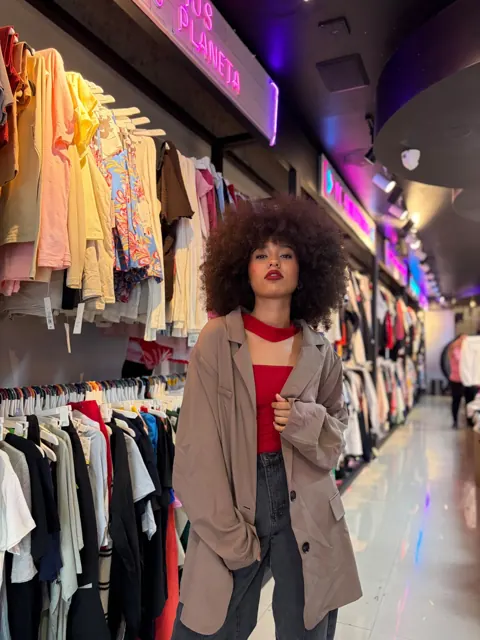 Modelo en un pasillo de Outlet de 99 rodeada de prendas de distintos colores
