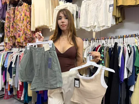 Modelo mostrando shorts y una prenda clara dentro de Outlet de 99