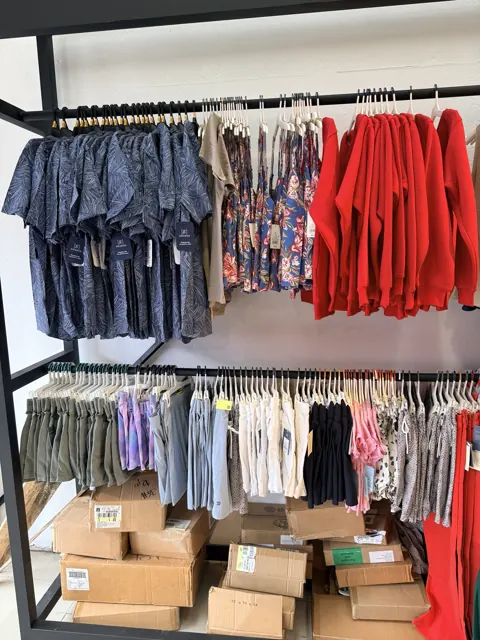 Rack con camisas, vestidos, sudaderas y pantalones en distintos colores