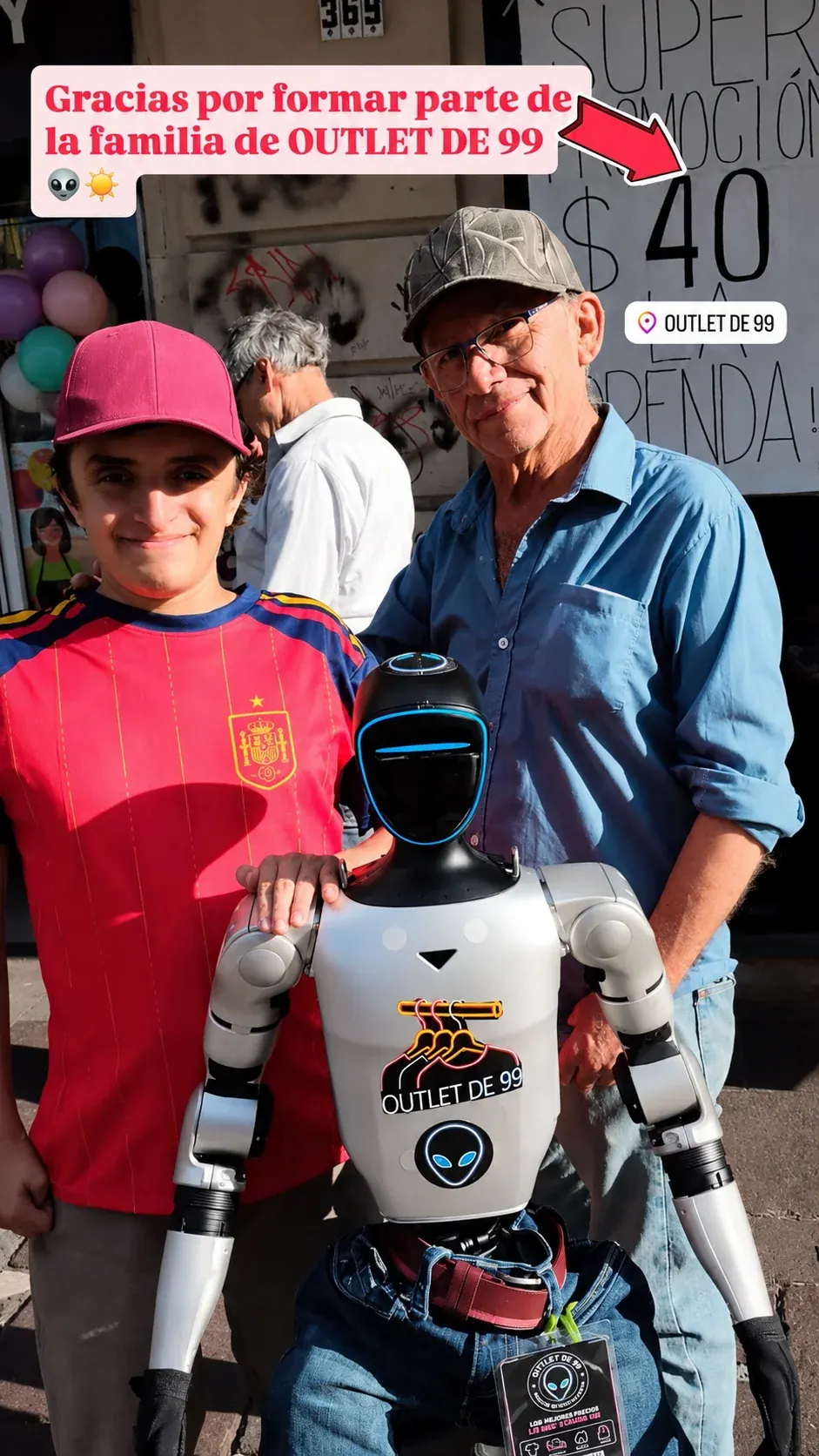 Marcianito 99, robot con el logotipo Outlet de 99, acompañado por visitantes